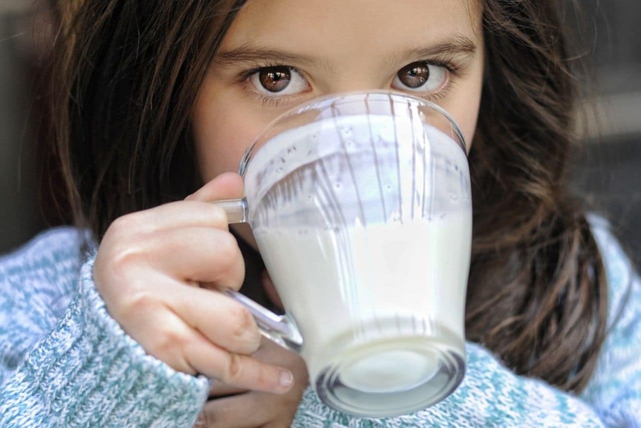 ragazza che beve latte da un bicchiere